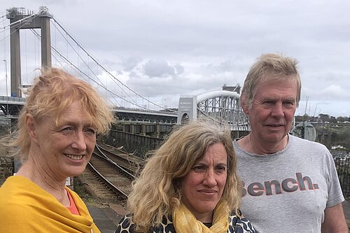 Three people, two women and one man, in the foreground, with the Tamar Crossing at Saltash in the background